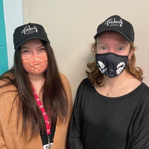 Two female volunteers wearing branded hats.