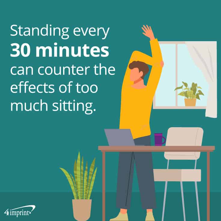 Person standing at their desk and stretching.