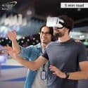 A man using virtual reality glasses next to a man wearing a lanyard.