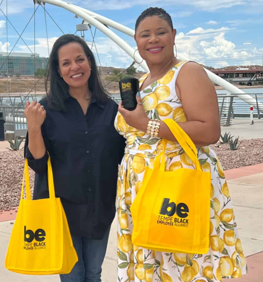 Two women smiling and holding tote bags
