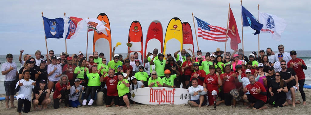 Large group of surfers and volunteers on the beach at an AmpSurf event.