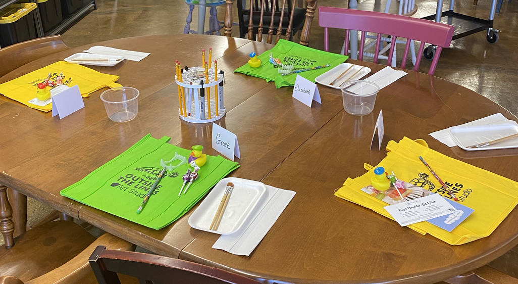 A table with supplies set up for an event at an art studio.