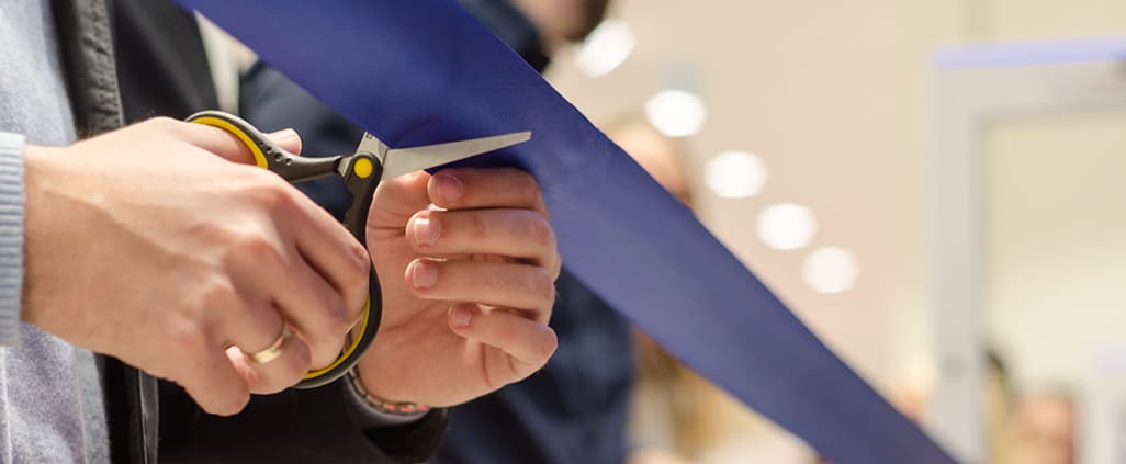Person cutting a ribbon at an event.