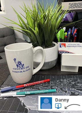 Branded white coffee mug next to pens and a plant