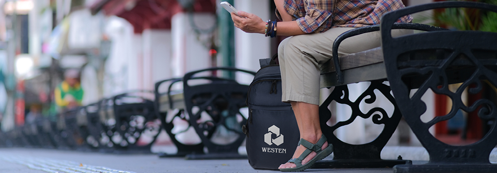 Person sitting on city bench with backpack sitting on ground next to her feet