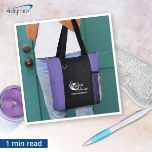 Foreground of person holding branded tote bag with background of pen, candle and eye mask.