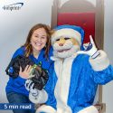 employee holding team holiday gift and posing with company mascot