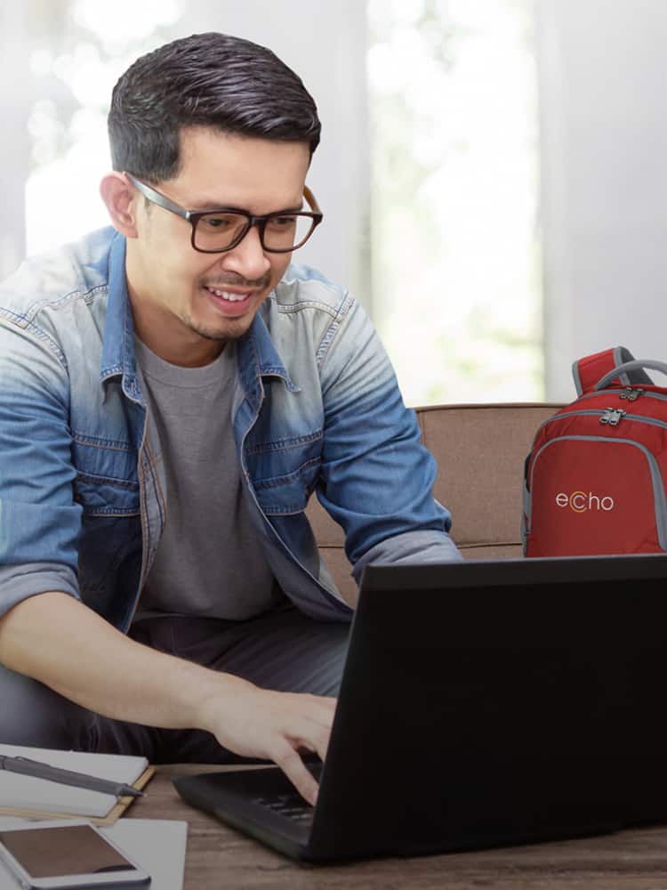 A man working on his laptop next to his branded laptop bag