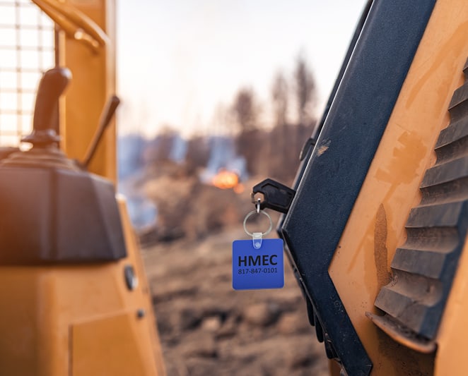A piece of heavy machinery with a key in the ignition. A logoed blue keychain is visible.