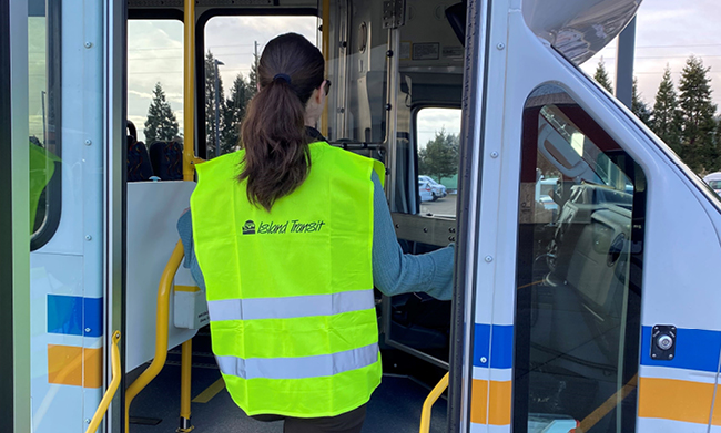 Person wearing Island Transit branded reflective vest stepping into a city bus