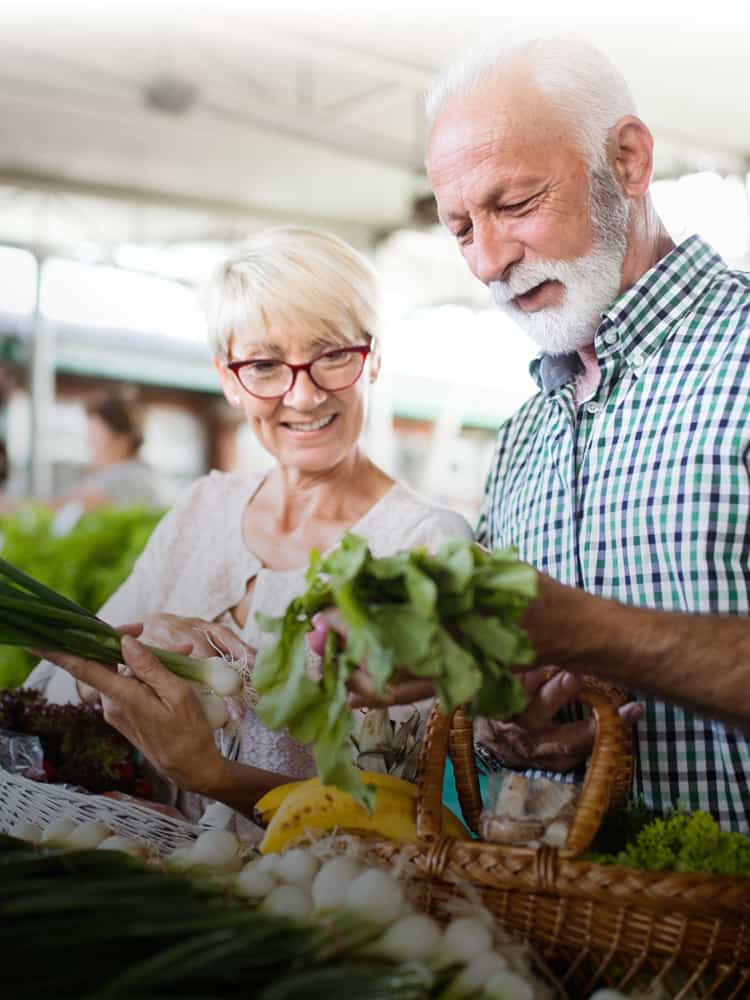 husband and wife looking at vegetables at farmers market