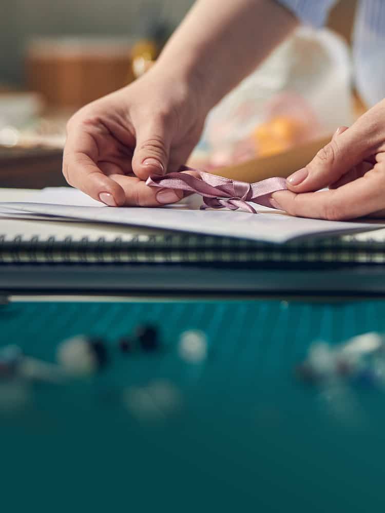 hands tying ribbon on thank you gift