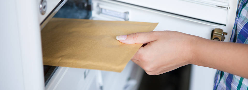 Person placing manila envelope in P.O. box