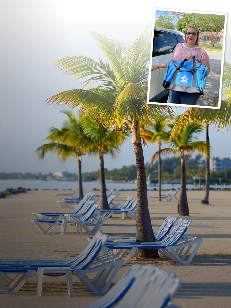Tropical beach with palm trees and lounge chairs with person holding Branded Duffel Bag