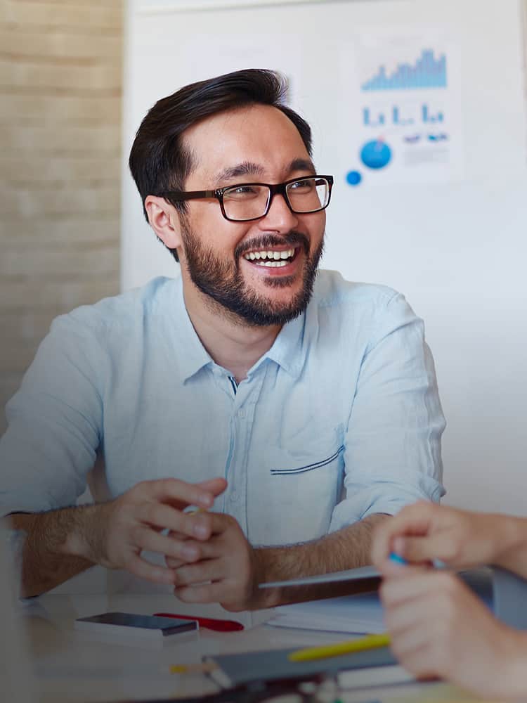 Man with glasses and blue polo talking at table