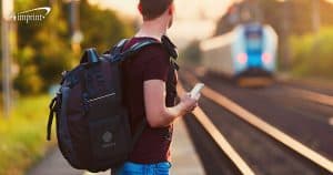 Person waiting for commuter train wearing laptop bag for employee. 2 min read time.