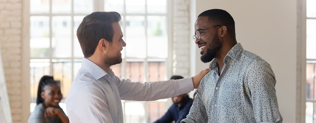 two co-workers shaking hands and showing gratitude at work