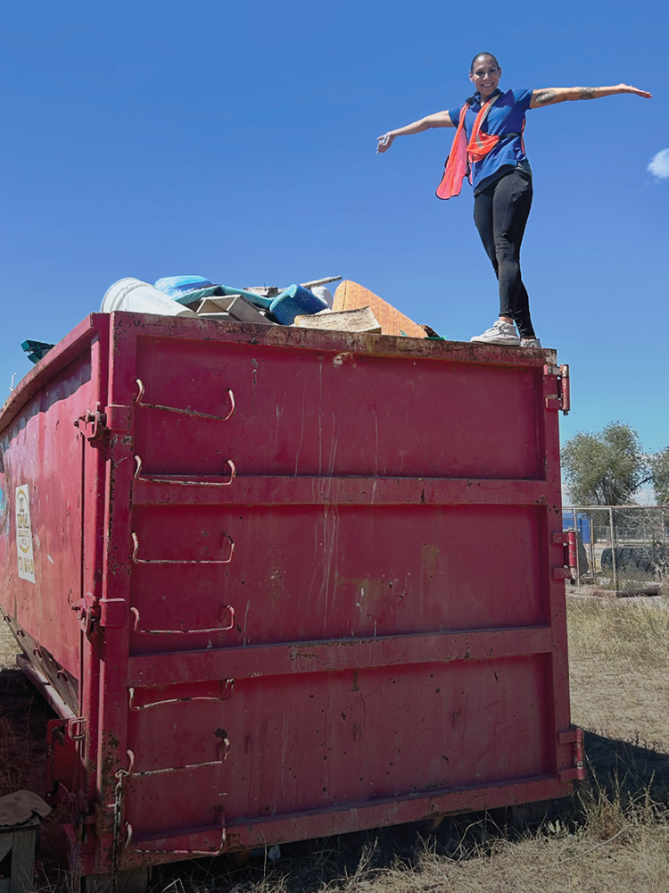 Woman stands on dumpster after community clean up