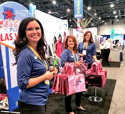 Three 4imprint employees handing out trade show promo products at their booth