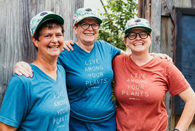 three employees wearing matching company baseball caps