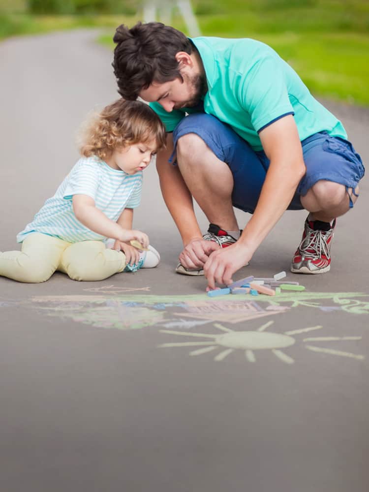 Father and daughter playing with sidewalk chalk.