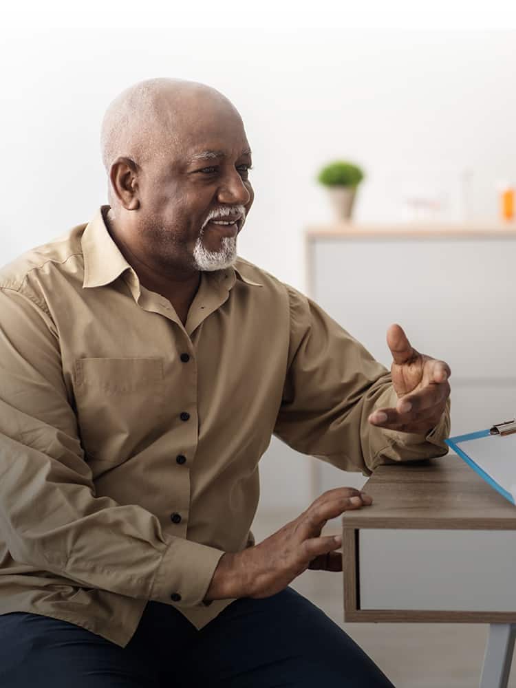 Man sitting at a desk talking with a doctor.