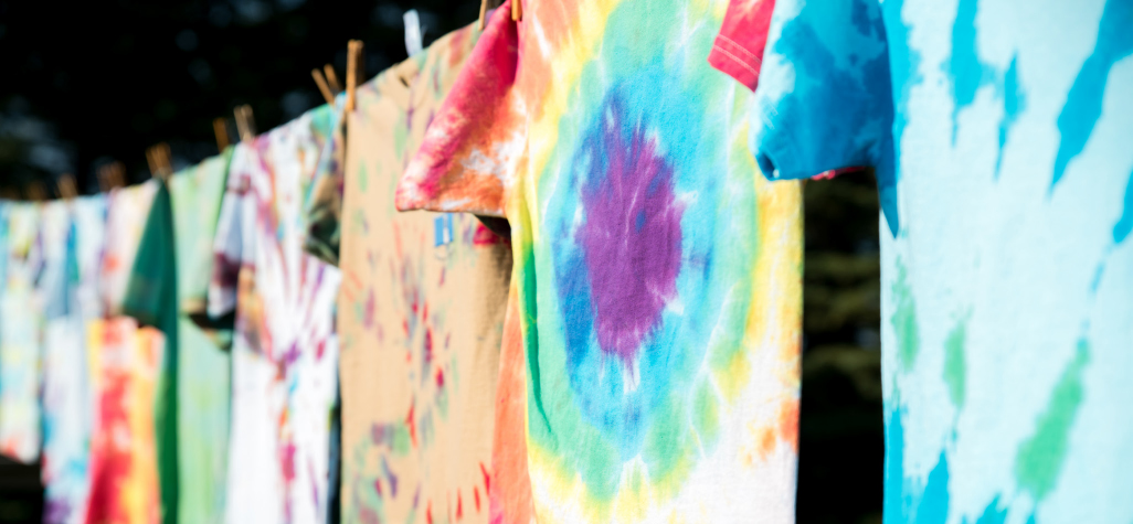 multiple different tie-dyed t-shirts hanging on a clothes line