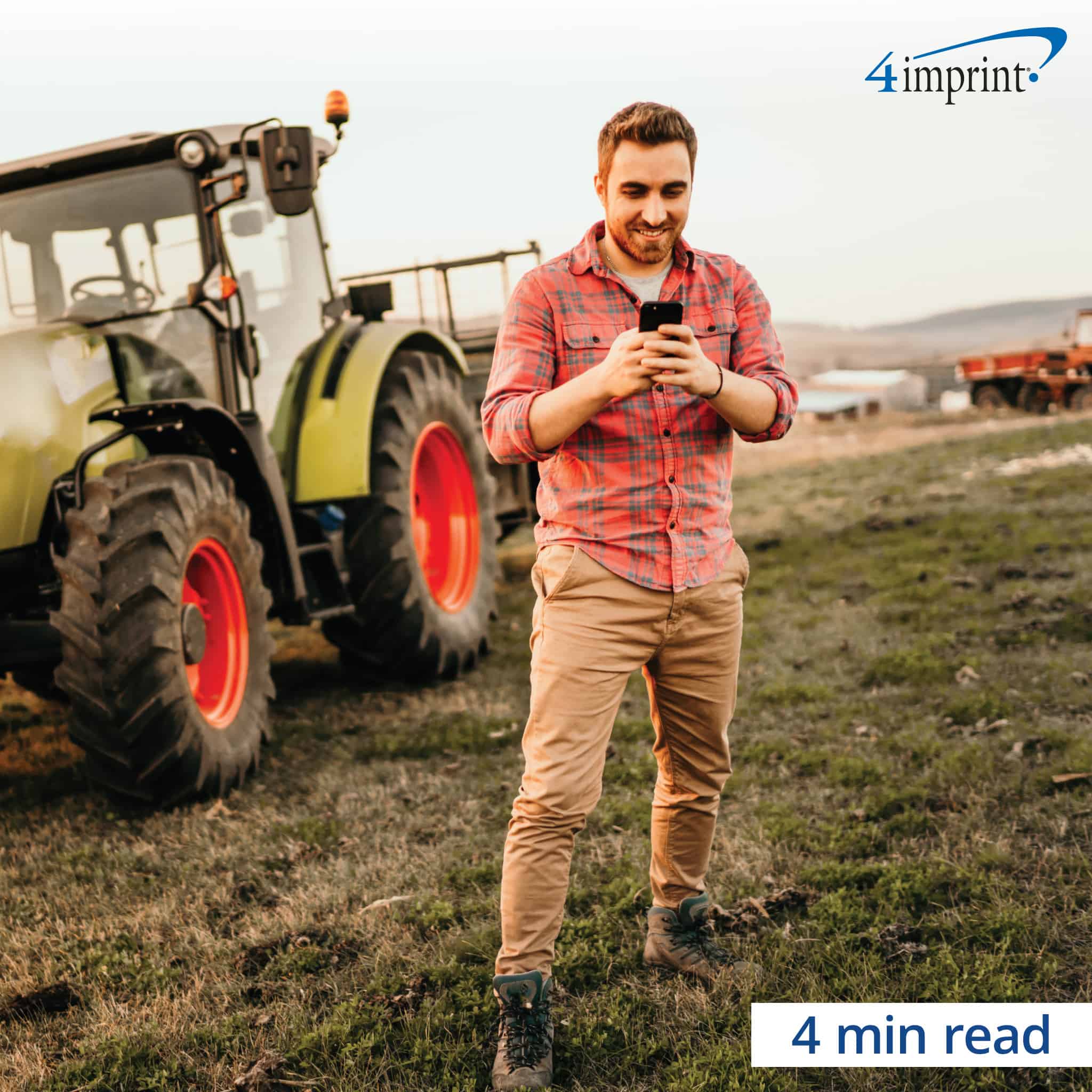 Farmer looking at cell phone with tractor behind him