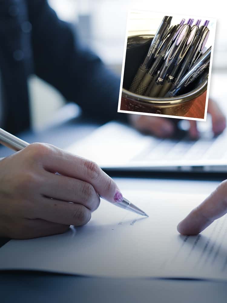 A cup of promotional pens superimposed over a person signing a document