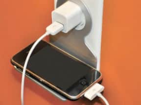 Smart phone laying on media charger and plugged into wall outlet