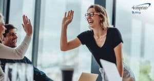 Two employees high-fiving each other over a table.