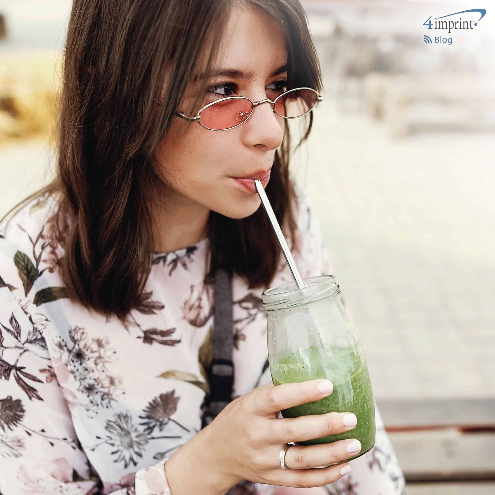 Picture of woman drinking smoothy with a branded reusable straw
