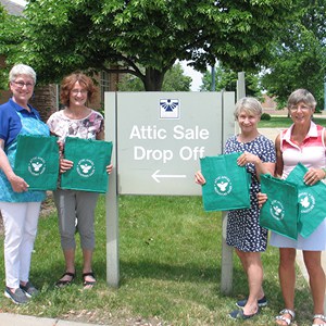 Attic Angel Volunteers holding custom reusable grocery bags.
