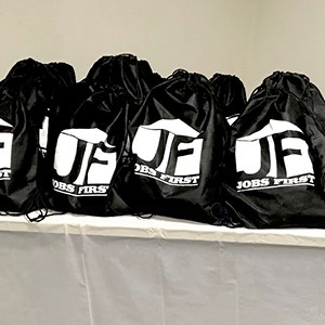 a pile of branded black drawstring bags sitting on a table | Harmony House | 4imprint bag giveaways