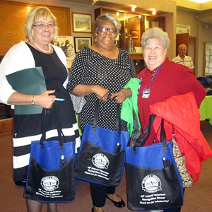 The RSVP volunteers hold custom screen-printed tote bags purchased with a one by one® grant.