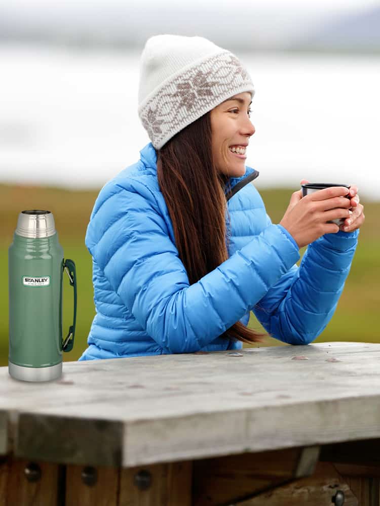 A woman drinking warm coffee from a thermos.