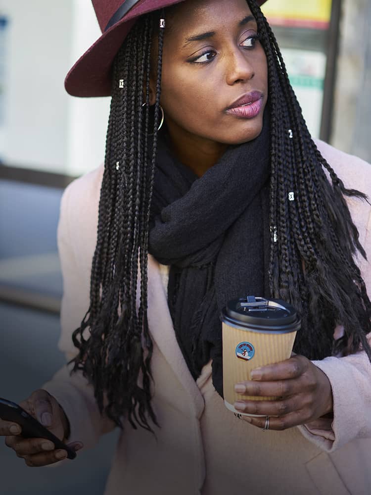 A woman walking outside holding cup of coffee