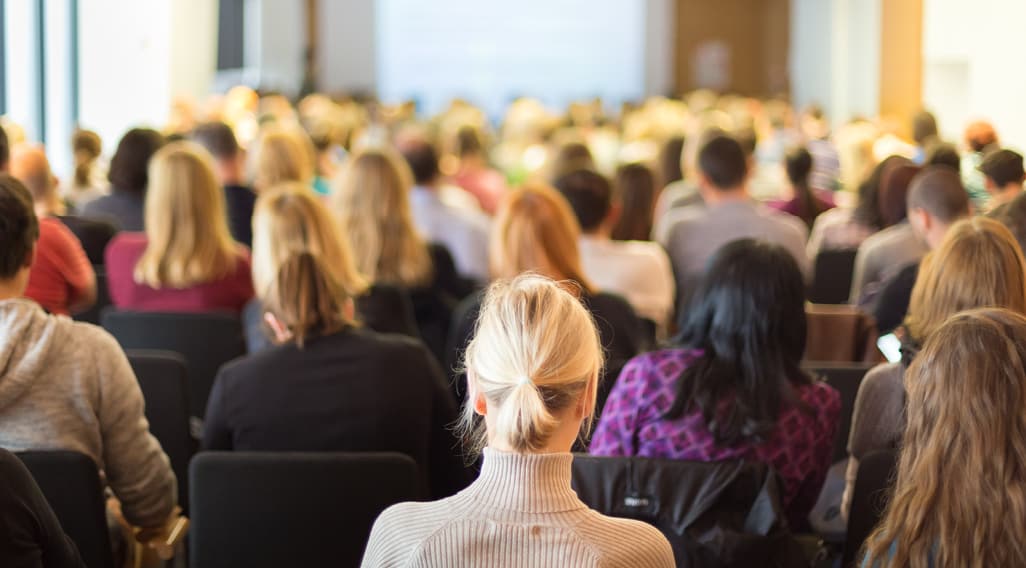 room filled with people listening to a speaker present - event giveaways