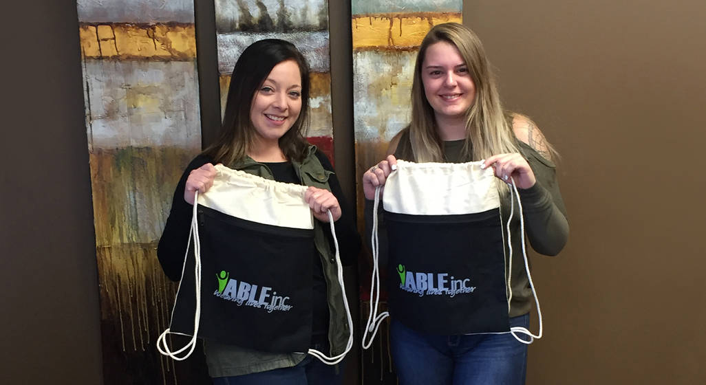 Two female employees holding branded promotional bags