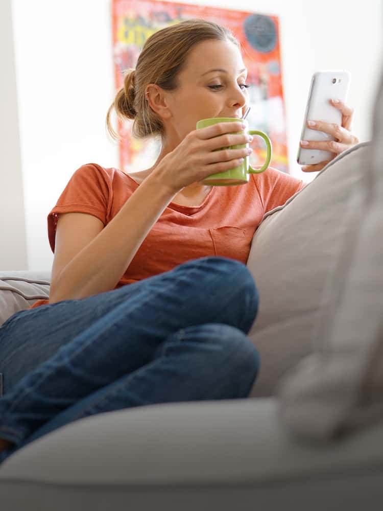 Woman sitting on couch at home with phone.