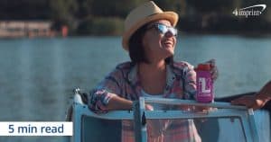 A woman sitting on a boat holding a drink in a promotional can cooler.