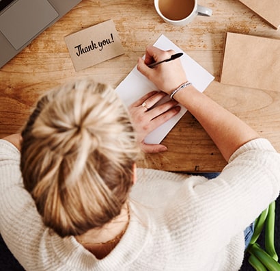 Person writing a thank-you card.