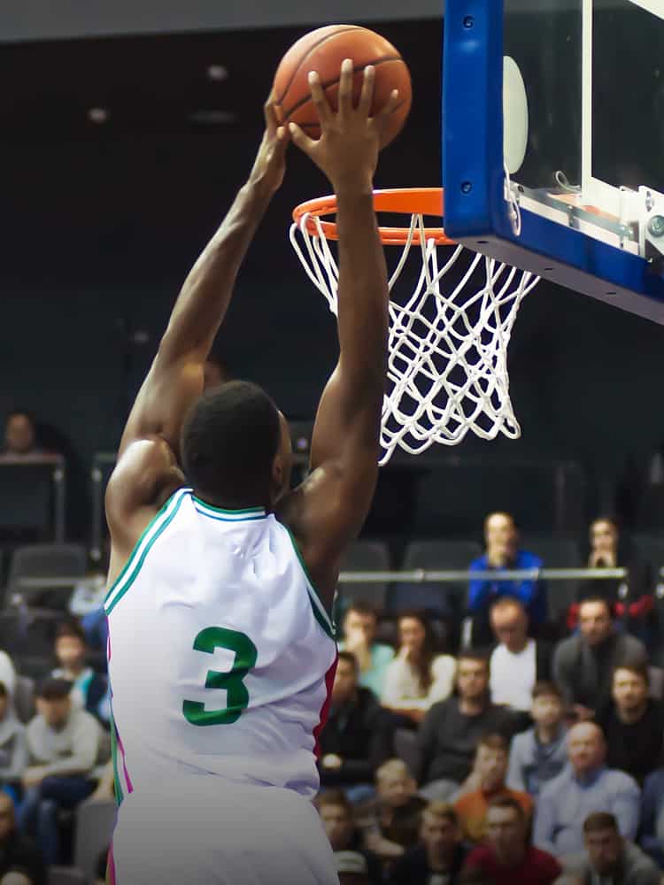 A basketball player performs a slam dunk.