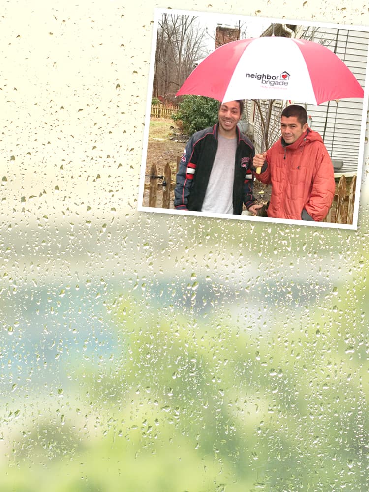Two men standing with Neighbor Brigade promotional umbrellas