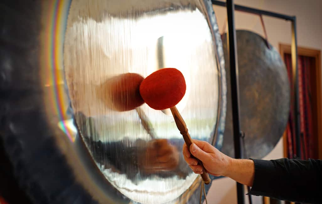 A person striking a gong with a mallet.