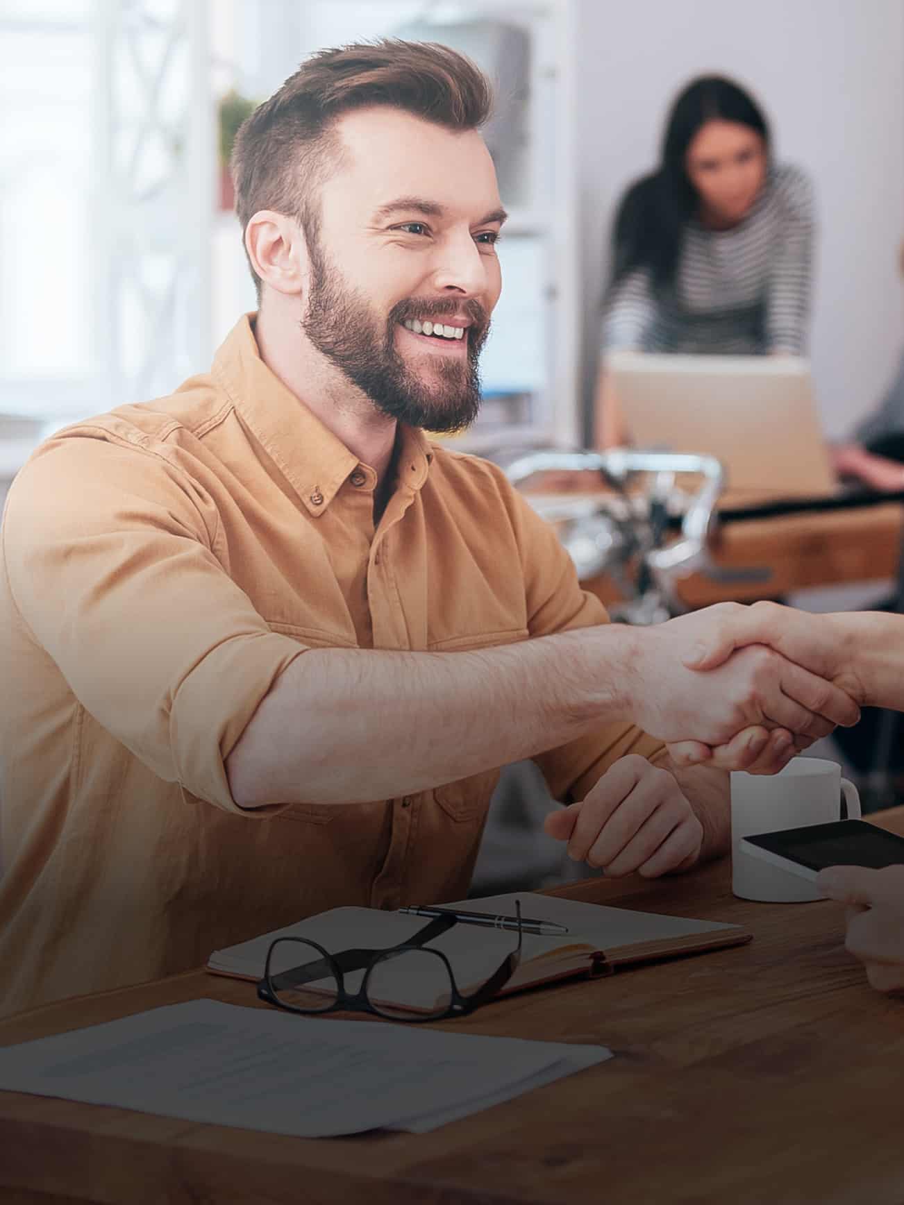 A man shakes hands with another man at a table.