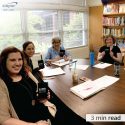 NAMI Wake County volunteers sitting in conference room holding 4imprint notebook gifts.