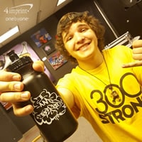 Teenage boy smiling and holding a black plastic water bottle